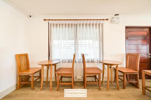 a group of tables and chairs in a room with a window at Chiangkhan Town Hotel in Chiang Khan