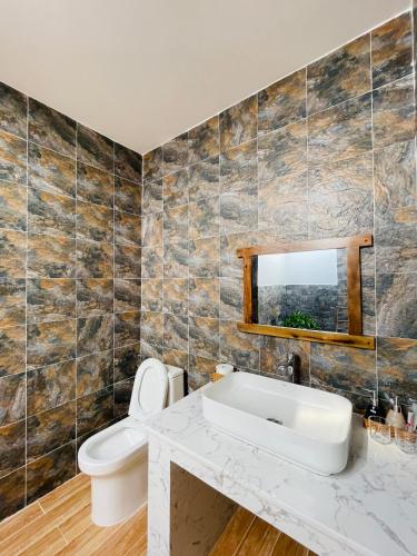 a bathroom with a sink and a toilet and a mirror at HOA Homestay Phu Quoc in Phú Quốc