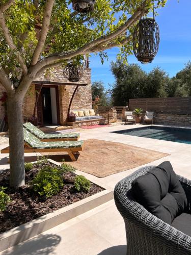 a patio with a chair and a tree and a pool at Peroulia Stone Villa Koroni - Grèce, Péloponnèse in Koroni