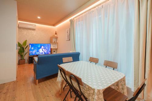 a living room with a table and chairs and a television at OHAYO Hotel 大森西 in Tokyo