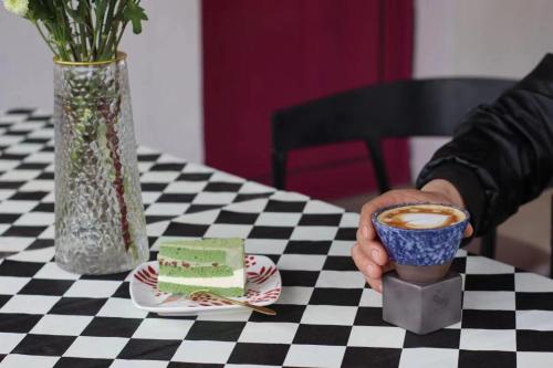a person holding a cup of coffee and a piece of cake at Encounter Garden Great Wall Holiday Guesthouse in Beijing
