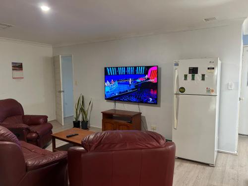 a living room with couches and a tv and a refrigerator at Celia's lovely house in Perth