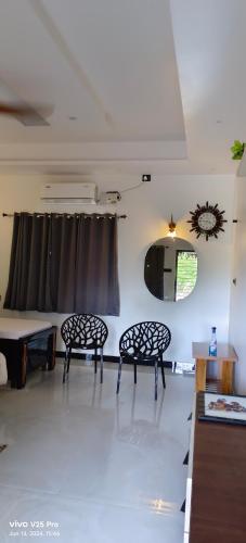 a living room with two chairs and a table at Saanvi Farmhouse in Hampi