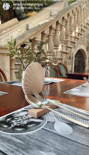 a wooden table with a plate and a fork and spoon at Rooms Miron - Adults Only in Sumartin
