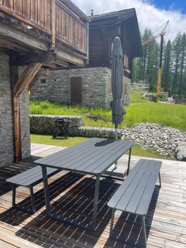 a picnic table with an umbrella and two benches at Polaris 1 001 - LUXE & SKI LIFT apartment 6 pers in Zinal