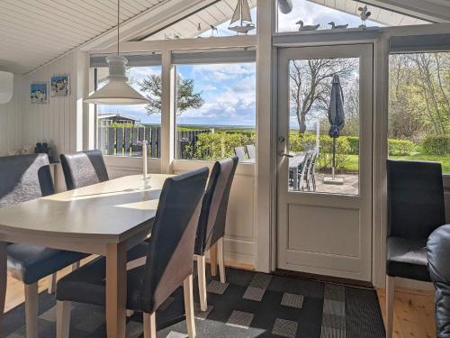 Spodsbjergにある4 person holiday home in Rudkøbingのテーブルと椅子と窓のあるダイニングルーム