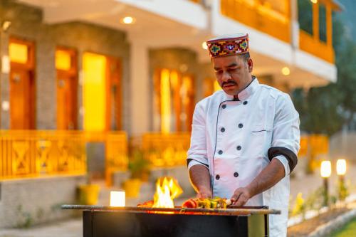 a chef preparing food on top of a grill at The Social Stays Kasol formerly ArtBuzz in Kasol