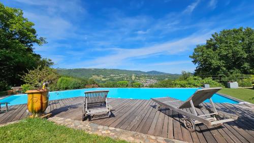 une terrasse avec deux chaises et une table à côté d'une piscine dans l'établissement Chambre d'Hotes Le Ponsonnet, à Conques-en-Rouergue