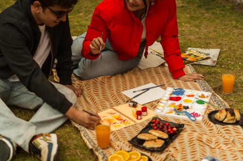 a group of people sitting on a picnic blanket with food at The Social Stays Kasol formerly ArtBuzz in Kasol