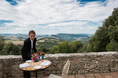 a woman standing next to a table with flowers on it at Borgo Pignano Tuscany in Pignano