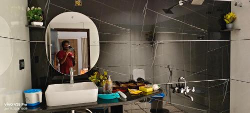 a woman taking a picture of a bathroom with a sink at Saanvi Farmhouse in Hampi