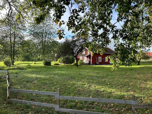 a fence in a field with a red house at Prästgården 303 Västra Tunhem in Västra Tunhem