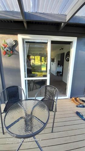 a table and chairs on a deck with a patio at Oak Lodge in Taheke