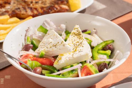 a bowl of salad with chicken and vegetables on a table at Drita Studios & Apartments in Svoronata