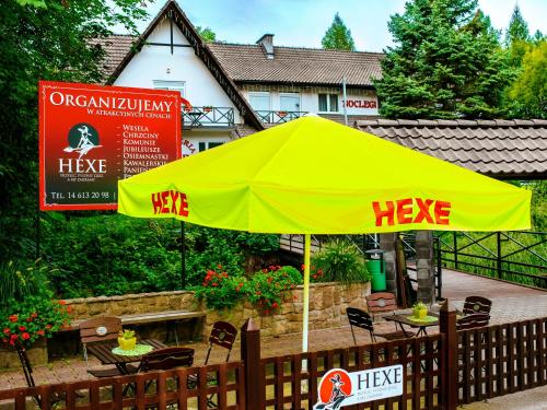 a yellow umbrella on a patio in front of a house at Noclegi Hexe in Żegocina