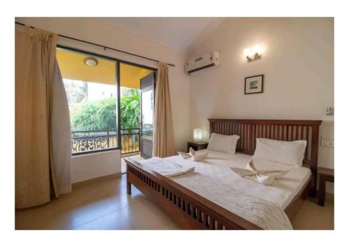a bedroom with a large bed and a large window at Lagoon Villa in Old Goa