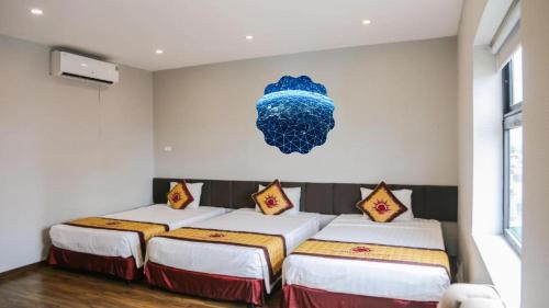 a room with three beds and a painting on the wall at Sunrise Hanoi Hotel in Hanoi