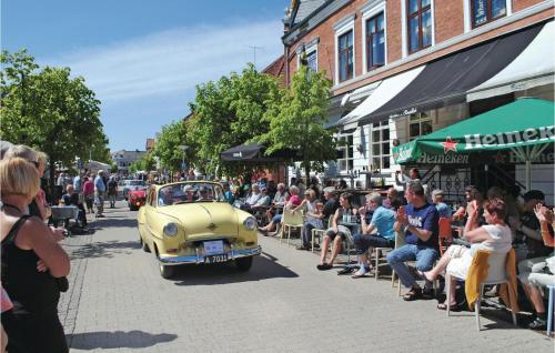 an old car driving down a street with a crowd of people at Apartment Havnevej Nykøbing Sj V in Nykøbing Sjælland