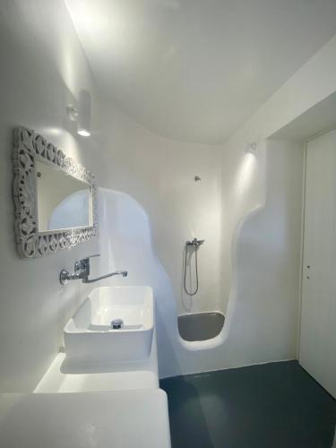 a white bathroom with a sink and a bath tub at Villa Irina Mykonos in Ftelia