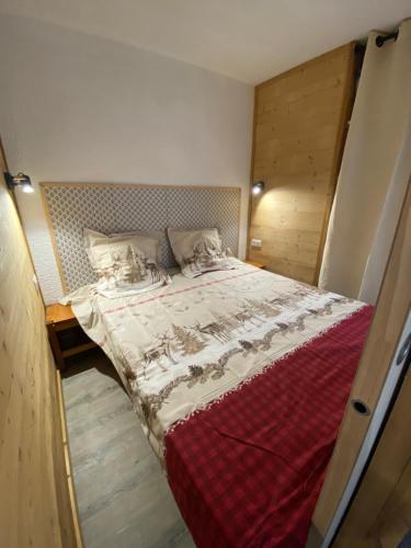 une chambre avec un grand lit avec une couverture rouge dans l'établissement Appartement pied des pistes, à Taninges