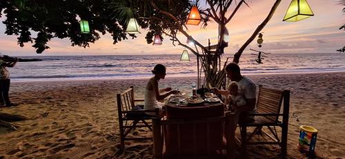 a man and woman sitting at a table on the beach at Breizh Cape Beach Bungalows in Ko Lanta