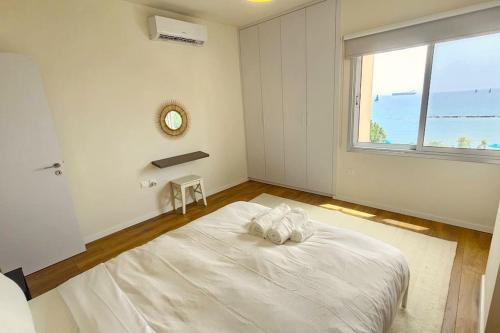 a white bedroom with a large bed and a window at Molos Beachfront City-Centre in Limassol