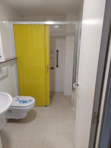 a bathroom with a toilet and a yellow door at Albergue Internacional de Llanes in Llanes