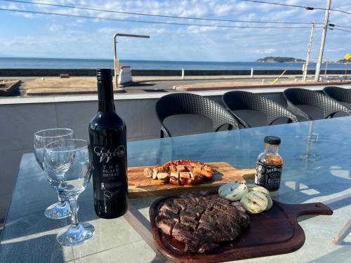 a table with a bottle of wine and a plate of food at オーシャンフロント館山 in Tateyama