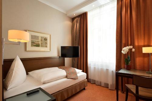 a hotel room with a bed and a desk and a window at Kastens Hotel Luisenhof in Hannover