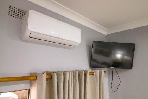 a flat screen tv hanging on a wall with a curtain at The Honeycomb 2 in Kimberley