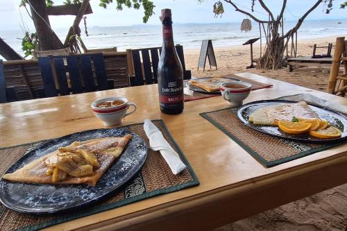 a table with a plate of food and a bottle of wine at Breizh Cape Beach Bungalows in Ko Lanta