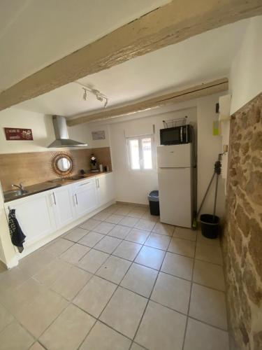 Il comprend une cuisine équipée d'un réfrigérateur blanc. dans l'établissement Maison de village Courthézon, à Courthézon