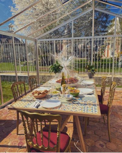 une table dans une serre avec de la nourriture dessus dans l'établissement Château de la PLUMASSERIE, à Fontenay-Trésigny