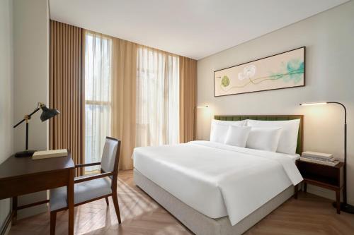 a bedroom with a large white bed and a desk at Epic Tower Swiss-Belresidences Hanoi in Hanoi
