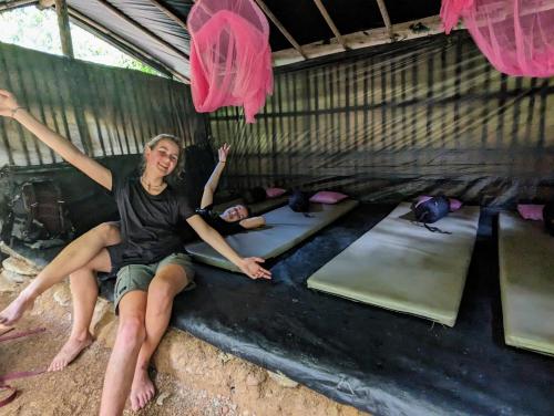 a woman sitting on a wall in a room with yoga mats at TheJungleGuide - Lodges & Treks in Bukit Lawang