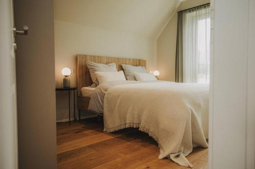 a bedroom with a bed with white sheets and a window at Nordsee Park Haus Stella in Dangast