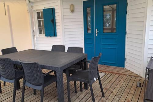 una mesa y sillas en un porche con una puerta azul en Mobil home 6 personnes, en Saint Gilles Croix de vie