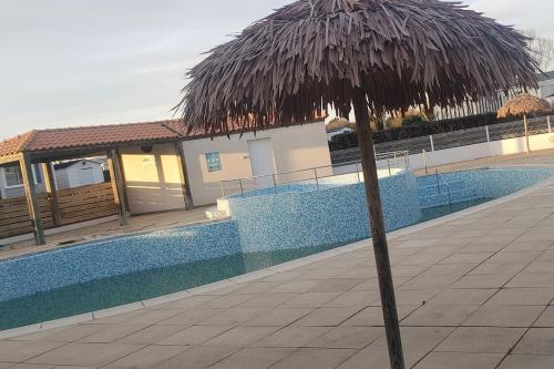 una sombrilla de paja junto a una piscina en Mobil home 6 personnes, en Saint Gilles Croix de vie