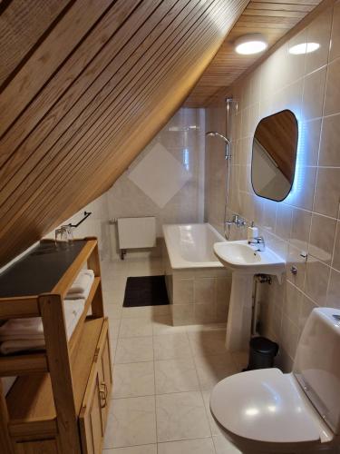 a bathroom with a sink and a tub and a toilet at Nidos burė in Nida