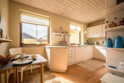 a kitchen with white cabinets and a table and a window at Lærke-huset in Bindslev