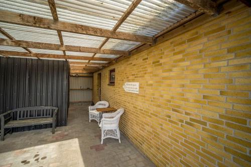 a brick wall with two chairs and a table at Lærke-huset in Bindslev