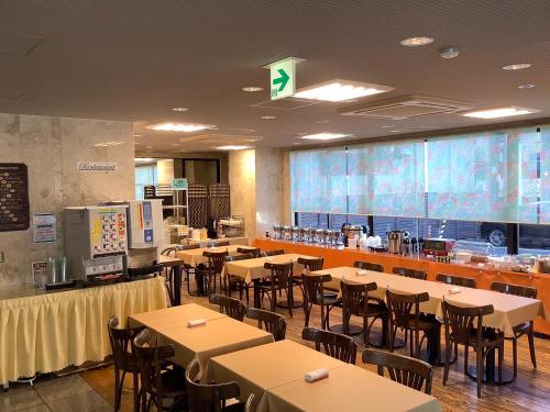 a dining room with tables and chairs and a large screen at Hotel Crown Hills Furukawa in Osaki