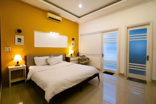 a bedroom with a white bed and yellow walls at Rose's House Hue in Hue