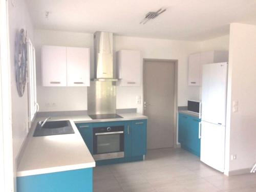 a kitchen with white cabinets and blue appliances at Villa Sanguinet proche Bassin d Arcachon in Sanguinet