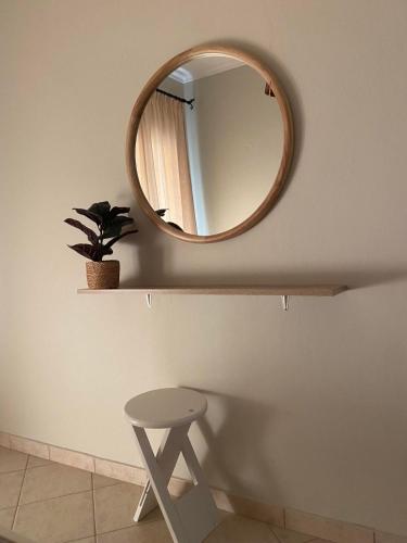 a mirror on a wall with a stool in a bathroom at S & S Apartment Preveza in Preveza