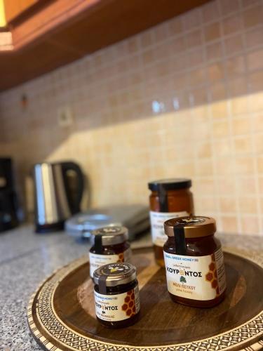 three jars of honey on a wooden tray on a counter at S & S Apartment Preveza in Preveza
