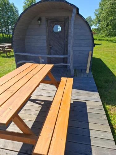a wooden picnic table in front of a yurt at Kempings Mežmalas in Usma