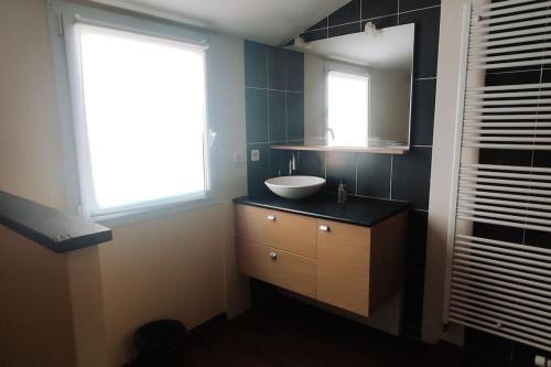 une salle de bain avec un lavabo, un miroir et une fenêtre dans l'établissement Maison Familiale, à La Verrie