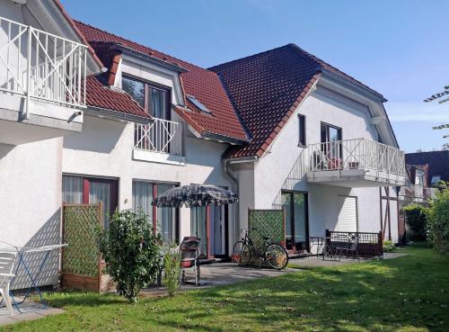a white house with an umbrella and a bike on a yard at Ferienwohnung mit Terrasse in Gustow