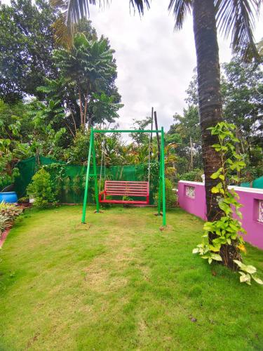 a park with a swing and a palm tree at Villoonnickal Homestay in Munnar